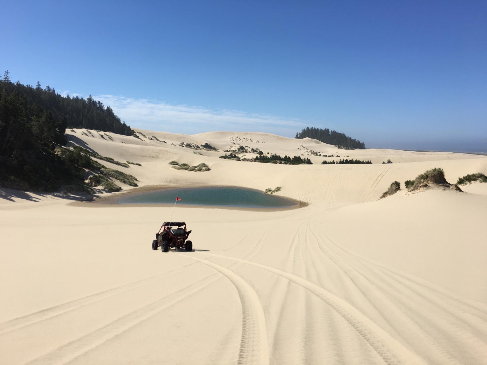 a dune buggy riding through sand dunes under a blue sky